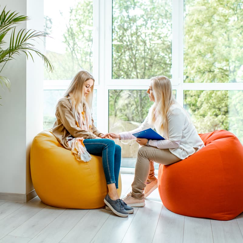 Dos personas conversando en un espacio luminoso junto a un ventanal
